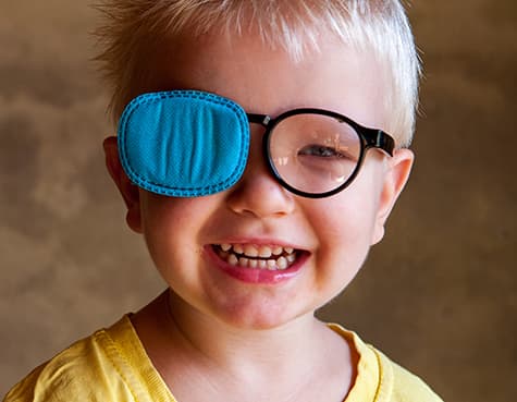 Boy wearing glasses with one lens blocked to treat lazy eye