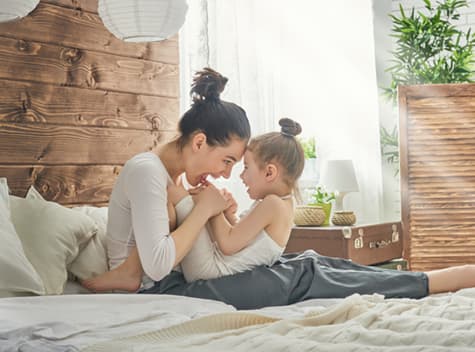 Woman playing with her child on bed